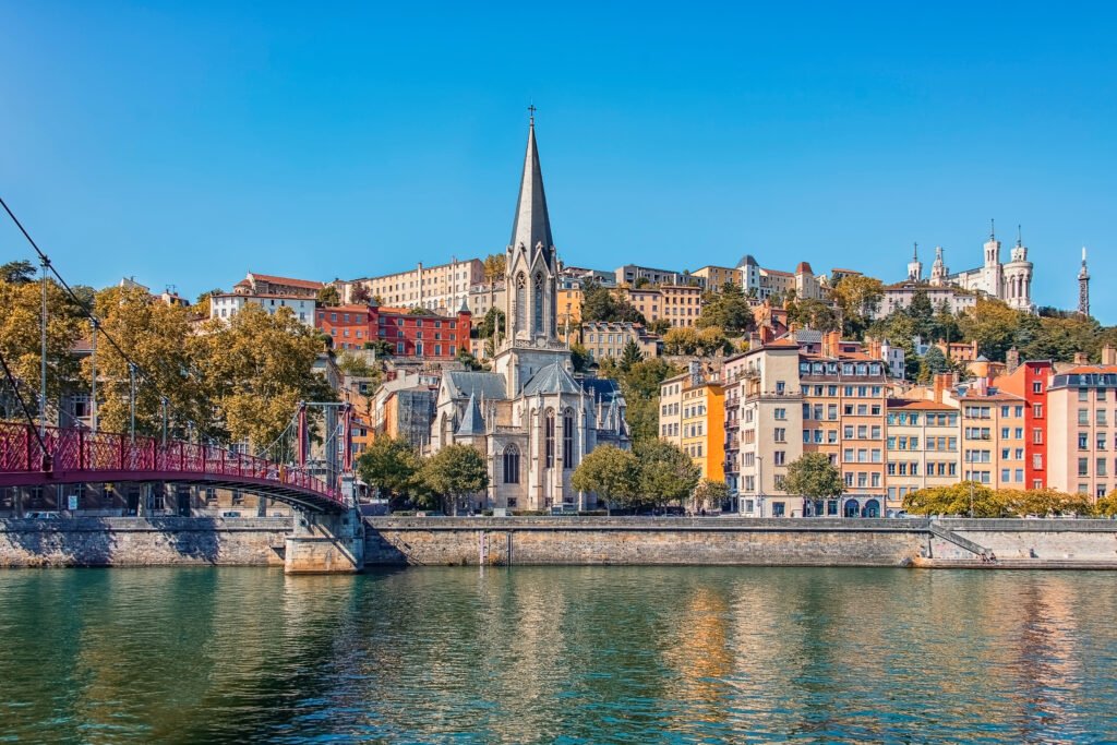 Historical Grandeur by the Banks of Lyon This image encapsulates the vibrant spirit of Lyon, with its historic architecture rising above the riverbanks, while the iconic red footbridge acts as a gateway to the city's rich cultural tapestry.