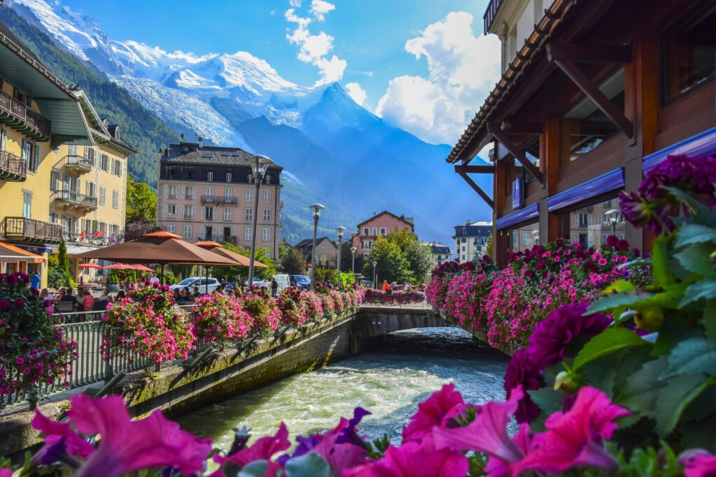 Alpine Serenity in a Mountain Town This vibrant image captures the essence of a picturesque town nestled in the valley, where the beauty of nature meets the warmth of village life, set against the stunning backdrop of the Alpine mountains.